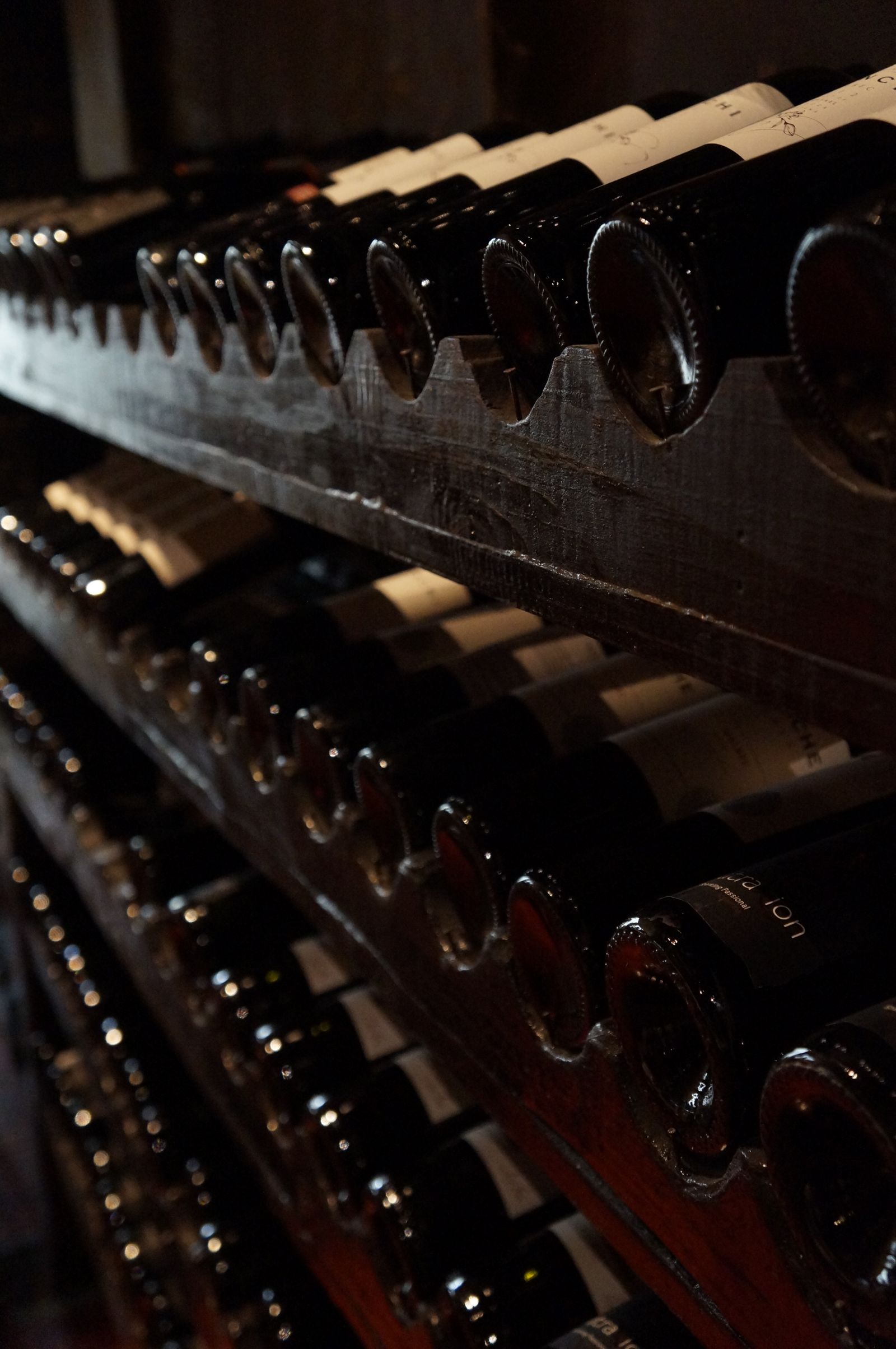 Liebherr wine cabinet with rows of aging bottles in low light — wine cabinet repair specialists