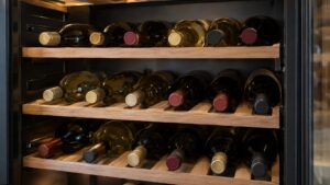A wine cabinet interior with bottles resting on wooden shelves